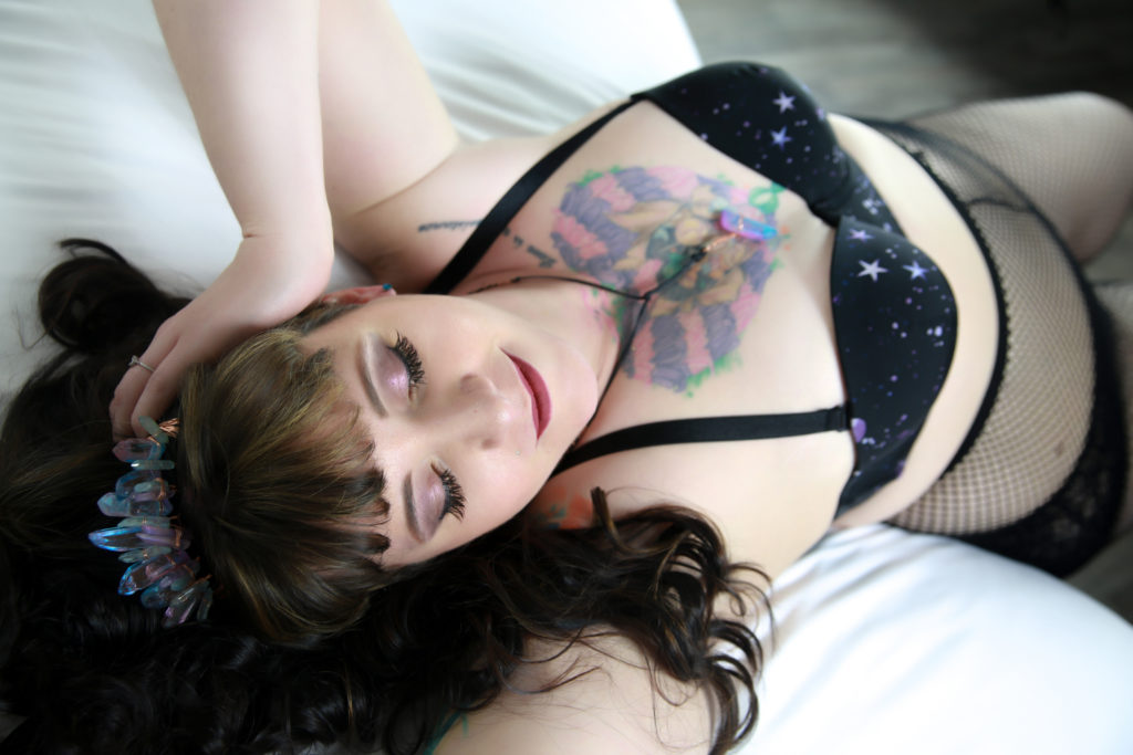 woman with lots of tattoos wearing a black bra and a headband with crystals on it
